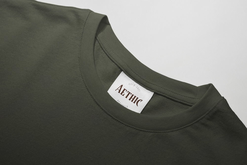 Close-up of a green t-shirt with a 'AETHIC' label on a gray background