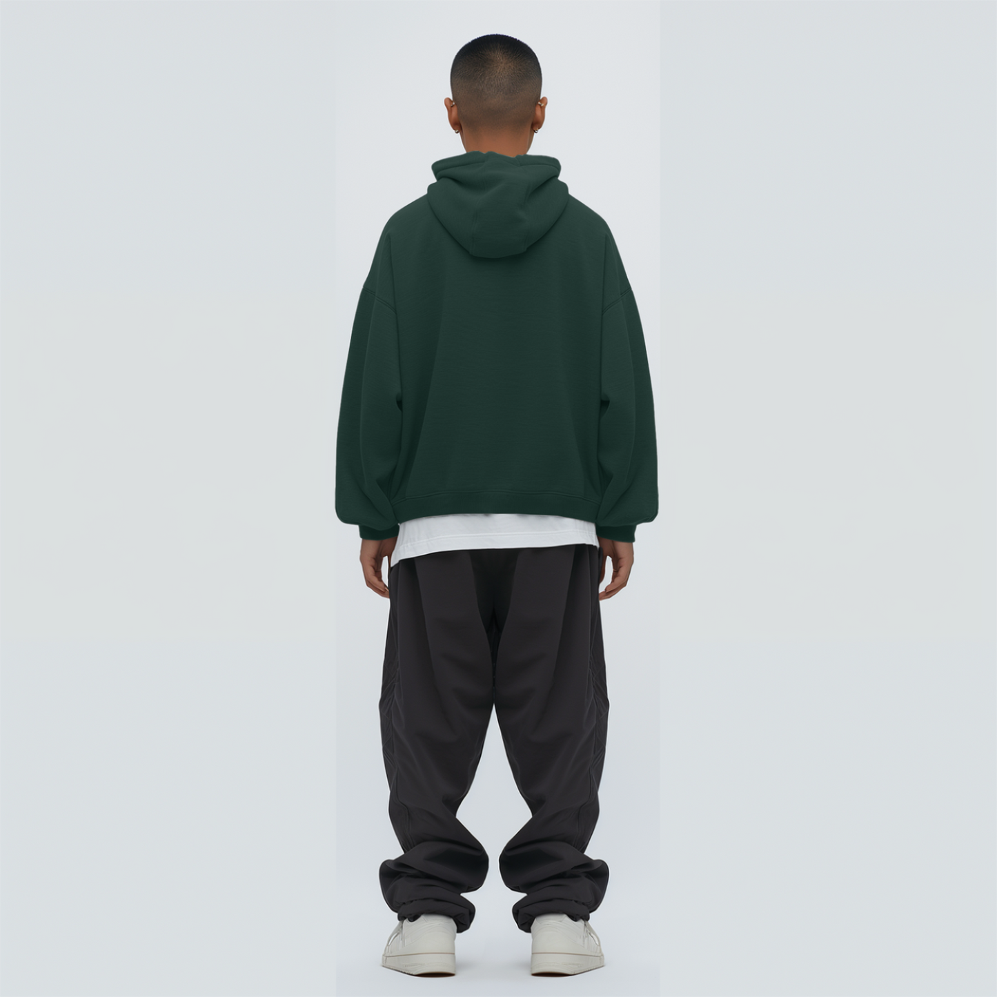 Person wearing a Bottle green hoodie and dark pants on a white background