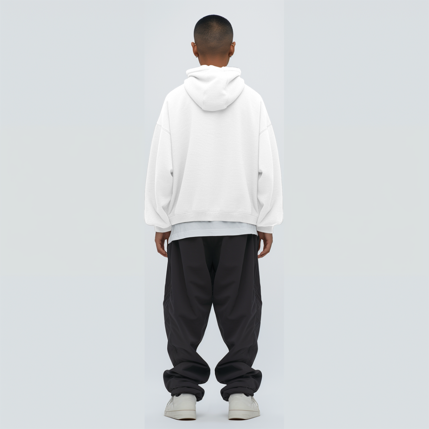 Person wearing a white hoodie and black pants on a light gray background