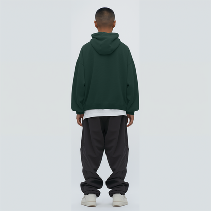 Person wearing a Bottle green hoodie and dark pants on a white background