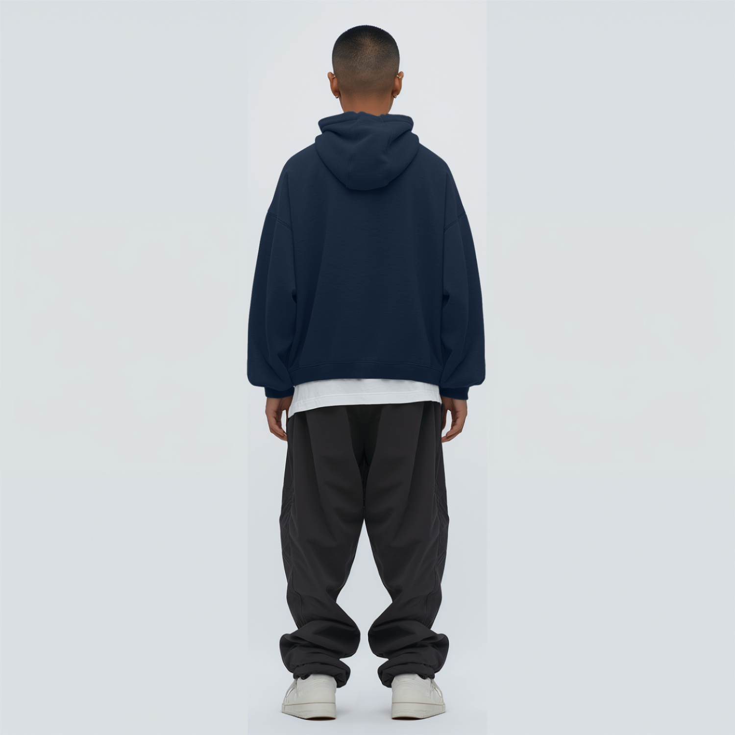 Person wearing a Navy blue hoodie and dark pants on backgrounda light gray 