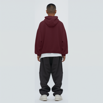 Person wearing a maroon hoodie and black pants on a white background