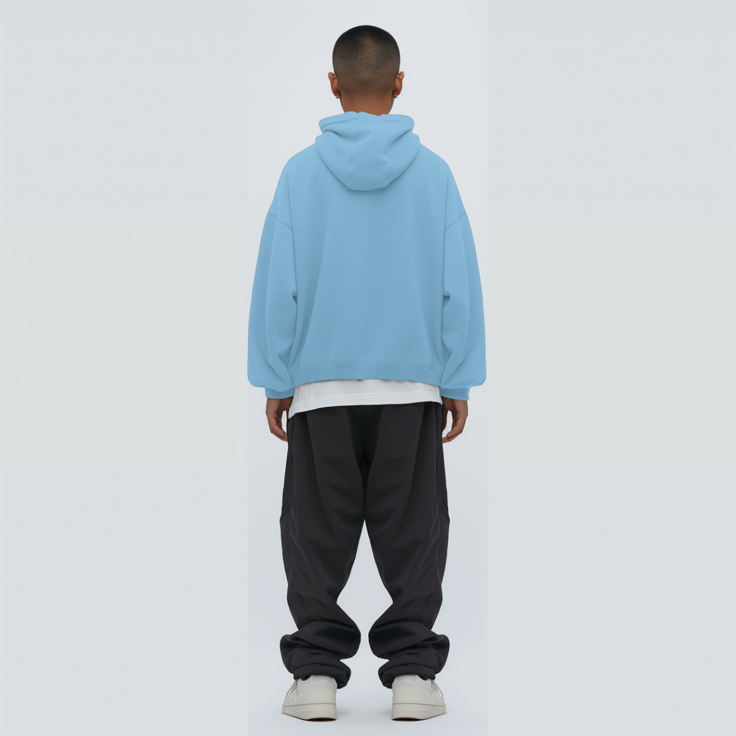 Person wearing a baby blue hoodie and dark pants on a white background
