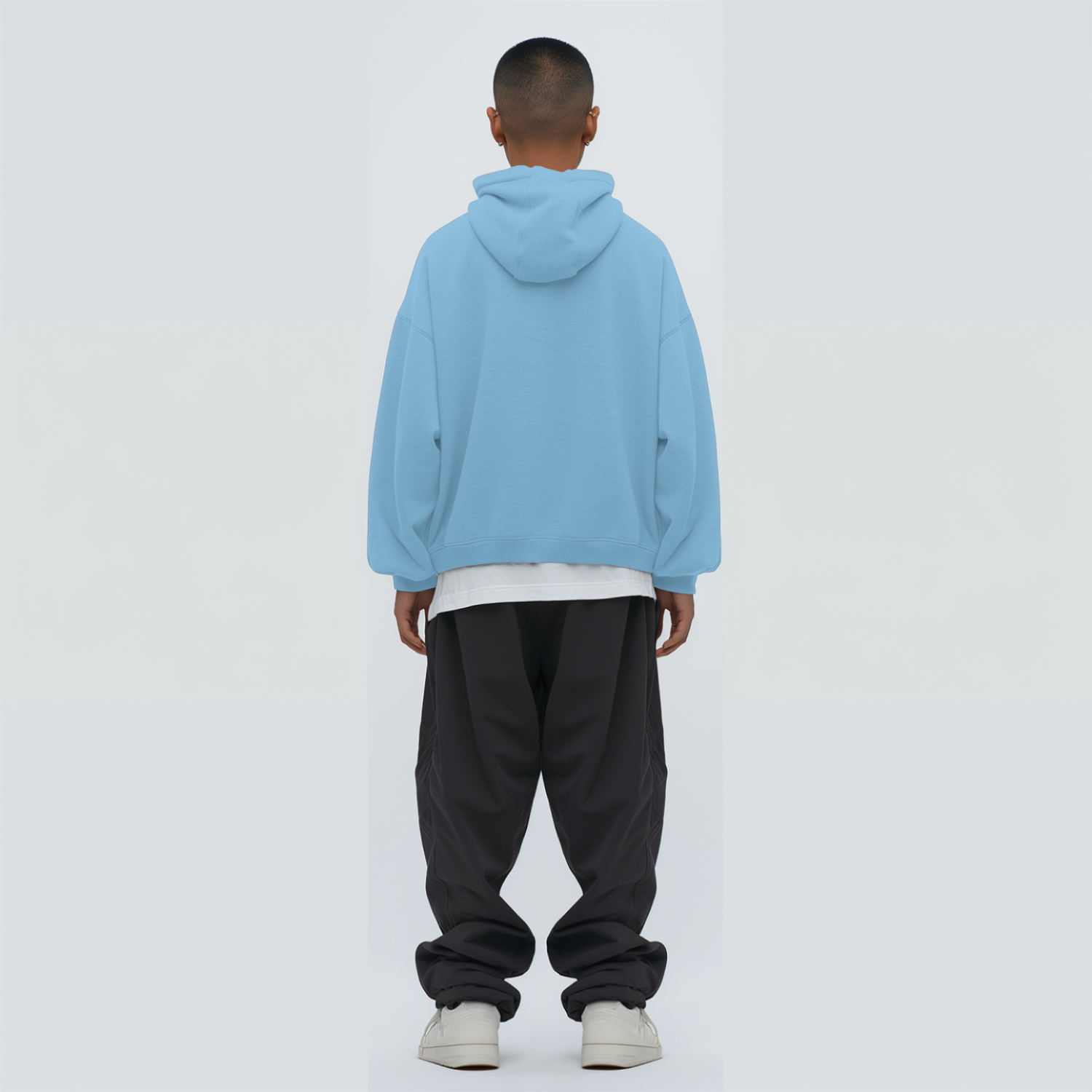 Person wearing a baby blue hoodie and dark pants on a white background