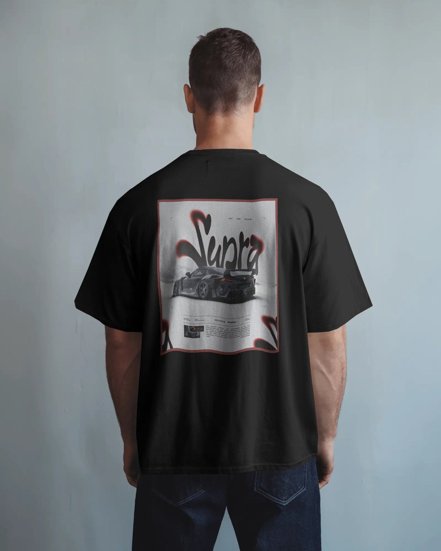 Person wearing a Colour_black t-shirt with a graphic design on the back against a plain background