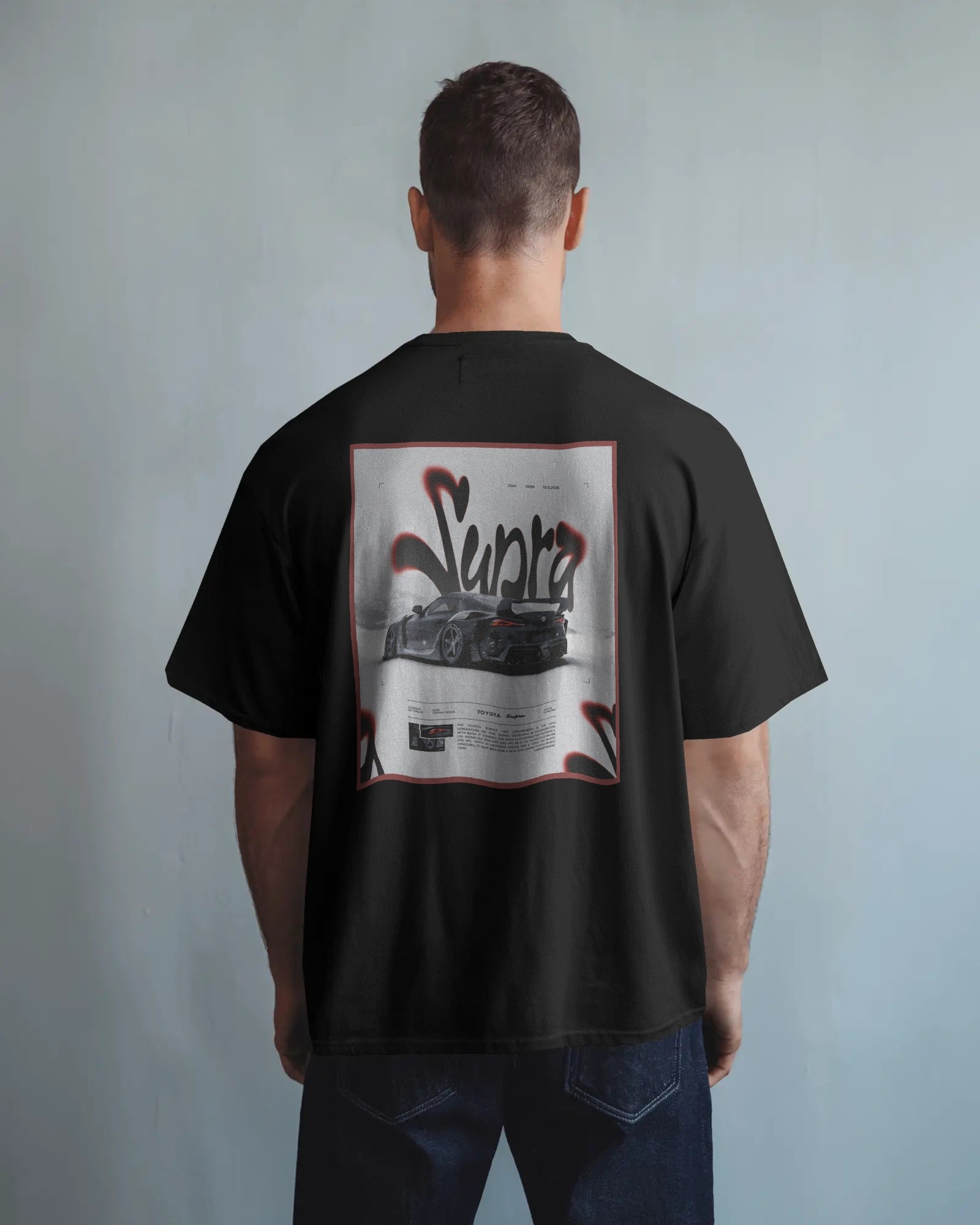 Person wearing a Colour_black t-shirt with a graphic design on the back against a plain background
