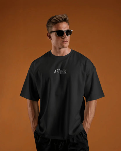 Man wearing a Colour_black t-shirt with 'Aethic' logo against an orange background