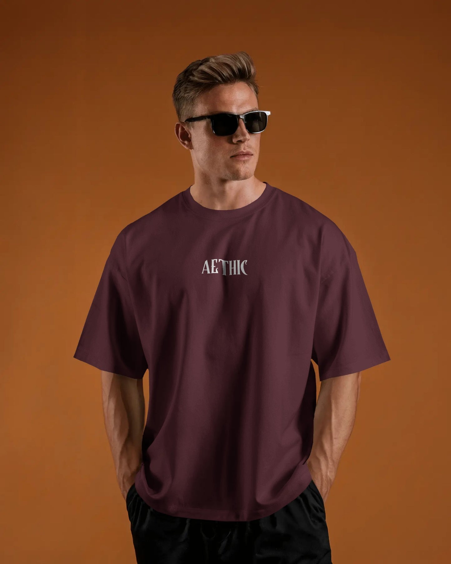 Man wearing a Colour_Maroon t-shirt with 'AETHIC' logo against an orange background
