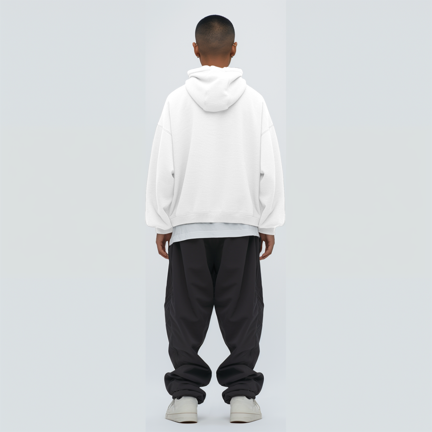 Person wearing a white hoodie and black pants on a light gray background