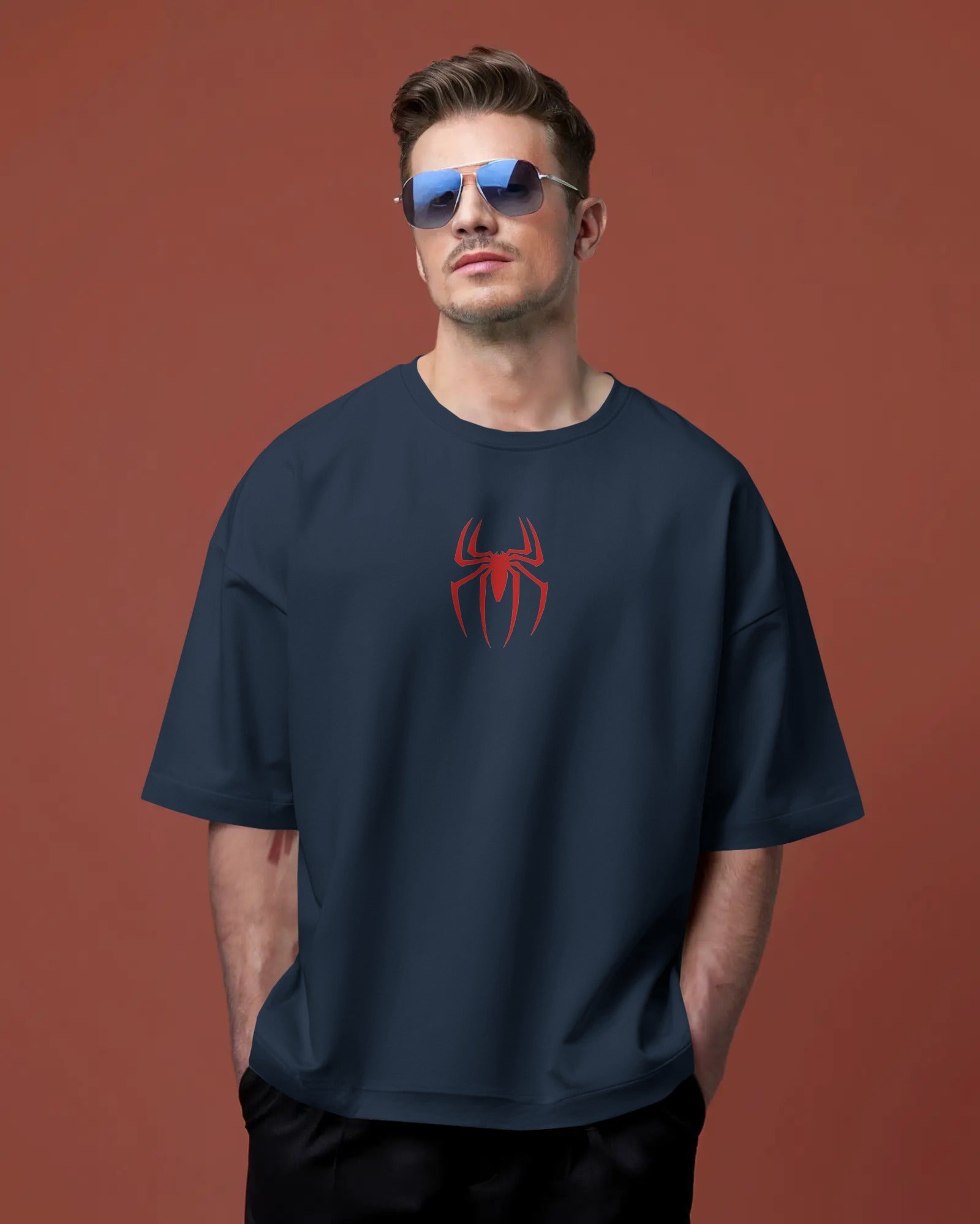 Man wearing a navy blue t-shirt with a red spider logo against a brown background