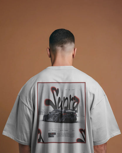 Person wearing a Colour_White t-shirt with 'Supra' logo and car graphic on the back against a brown background