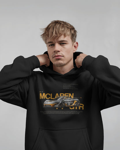 Person wearing a Colour_black  hoodie with McLaren logo and car graphic on a gray background