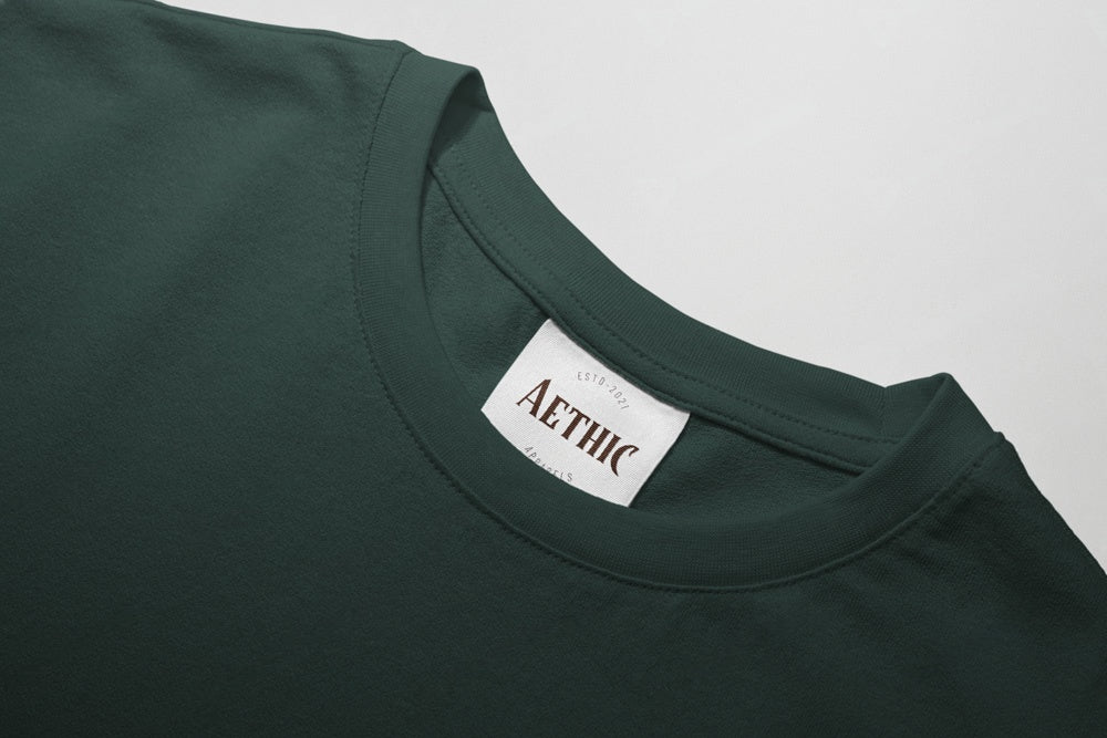 Close-up of a green t-shirt with 'AETHIC' label on a gray background