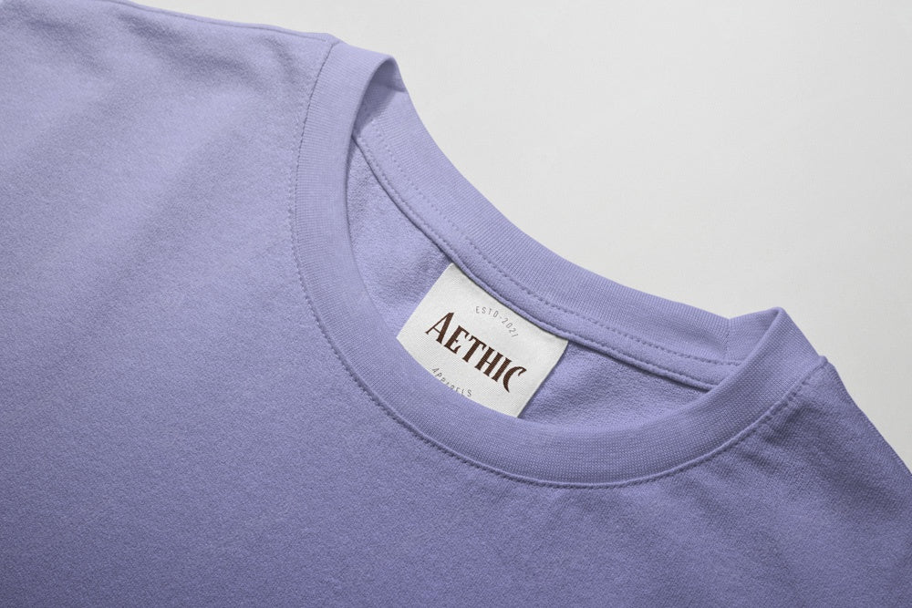 Close-up of a purple shirt with a 'AETHIC' label on a light gray background